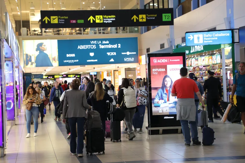 Interior del Aeropuerto de Tocumen mostrando a muchos pasajeros con maletas y pantallas de anuncios en Terminal 2.